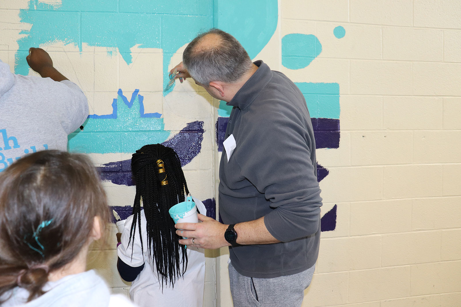 DMi MLK Day volunteering at Stephen Girard Elementary School, adults and children painting a school wall