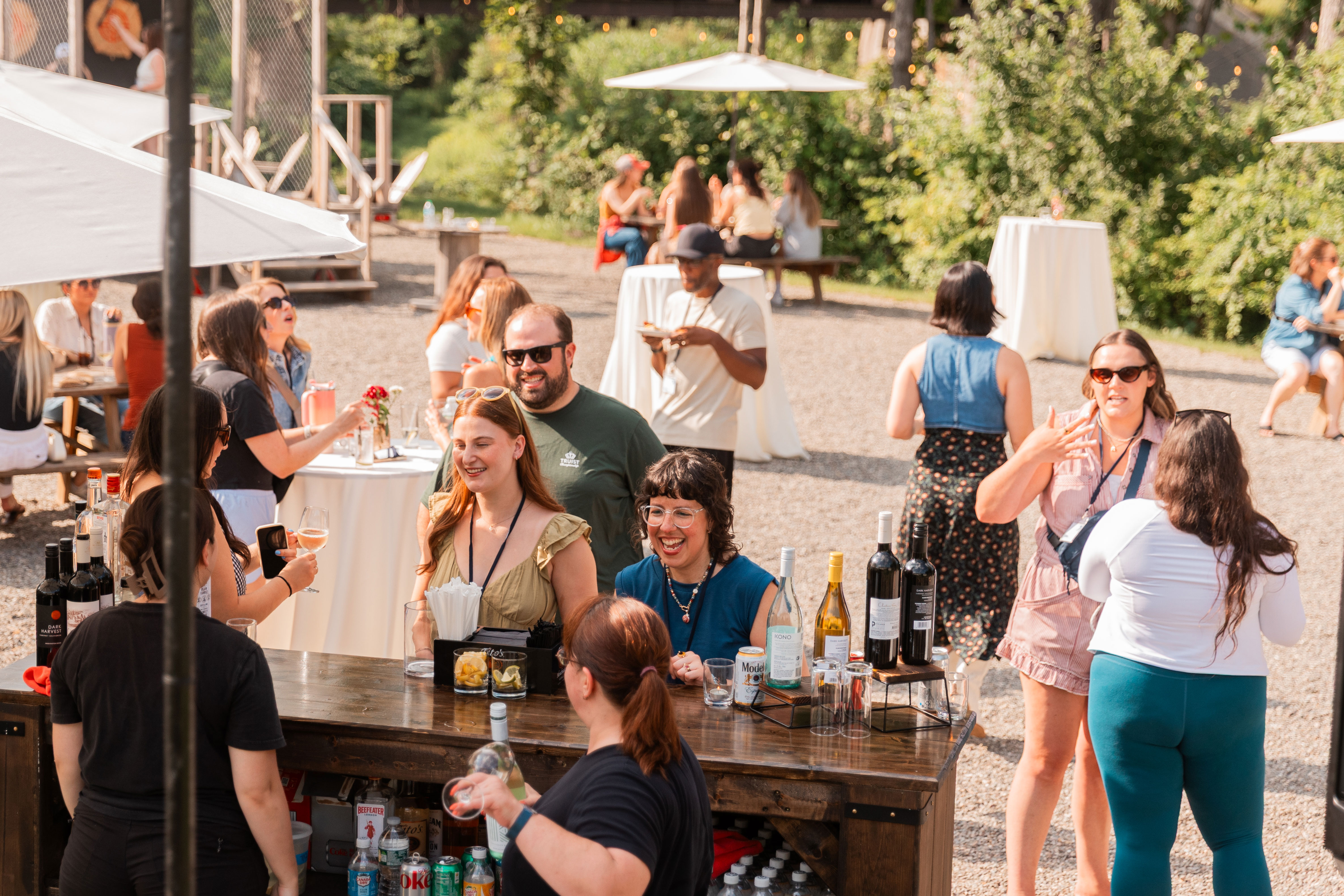 DMi Partners employees socializing at an outdoor company event with drinks and high-top tables